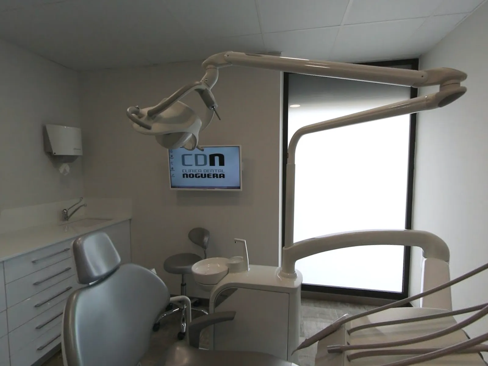 Gabinete con sillón dental y el logo de la clínica en el monitor